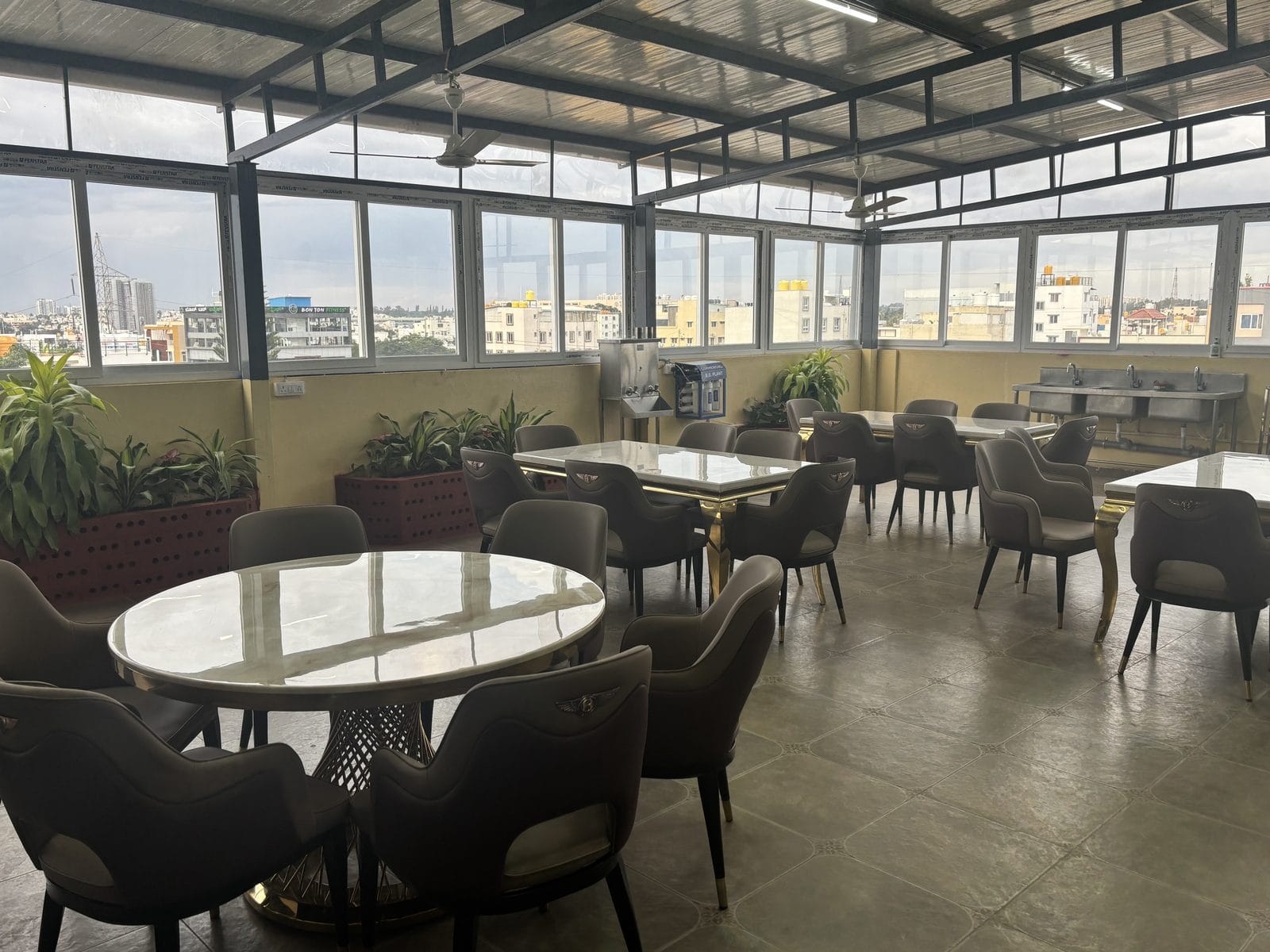 The rooftop dining hall at Infinity Space PG, Yeshwanthpur — glass-walled, with tables, a water purifier and a city view